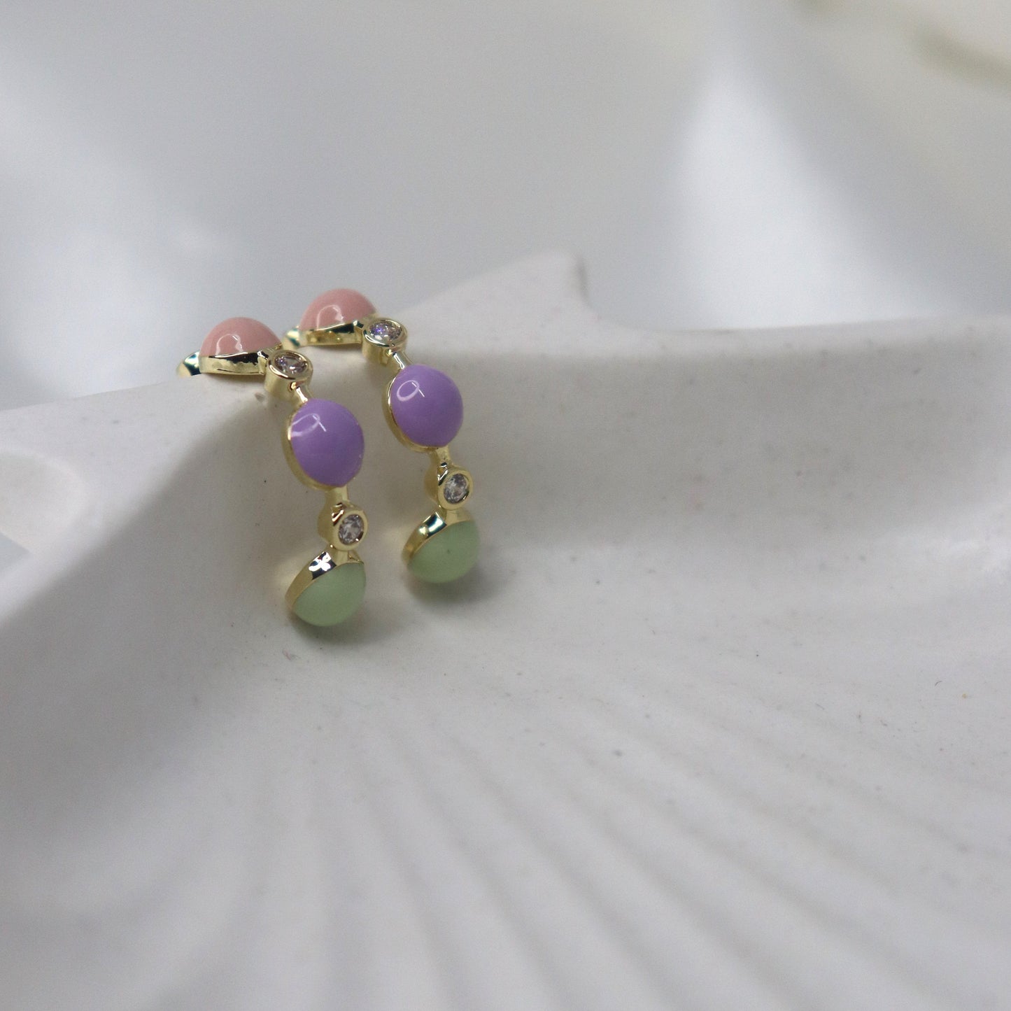 Small earring with colorful beads on a white shell background