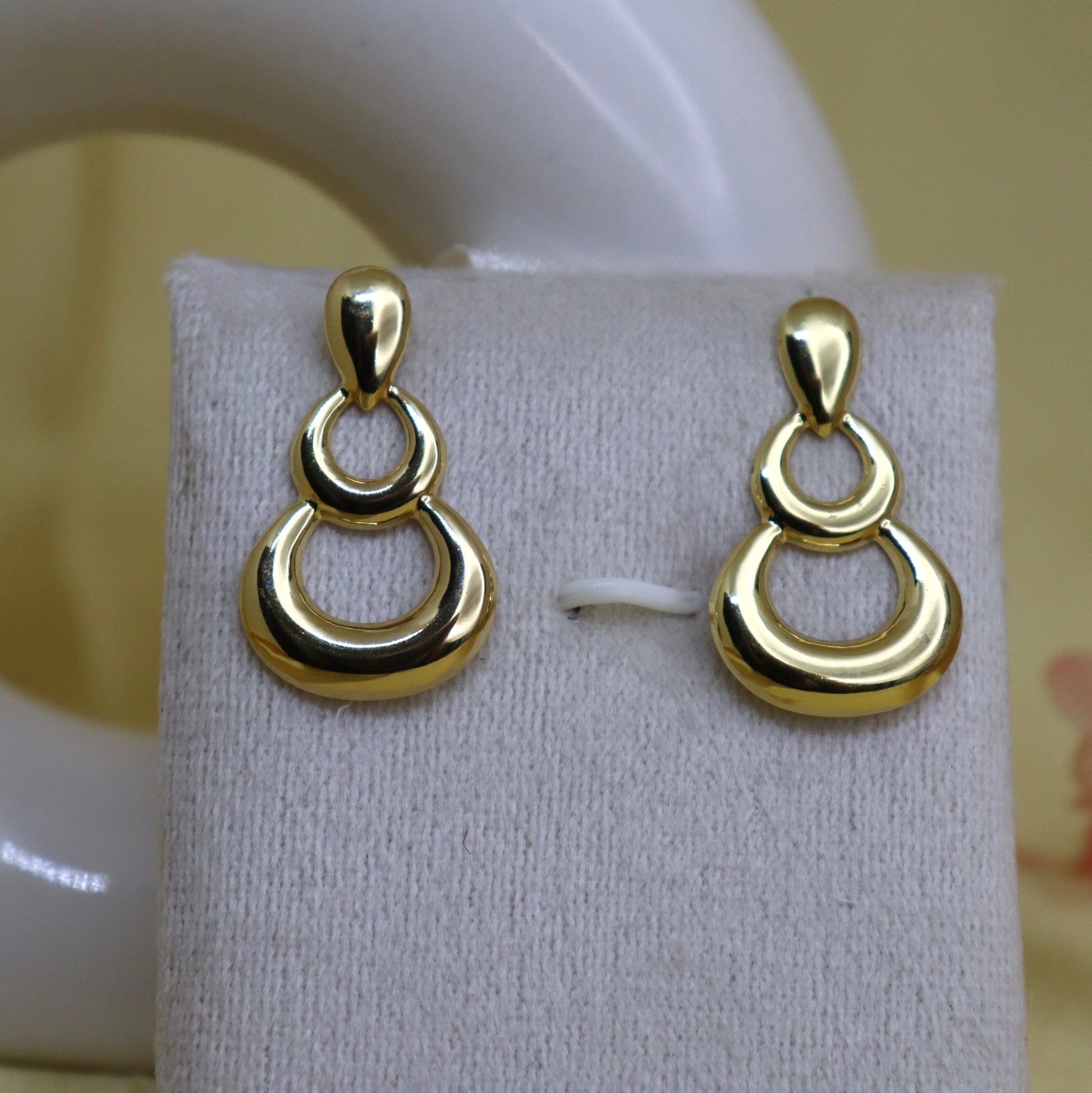 Gold earrings on a white display card with a blurred background