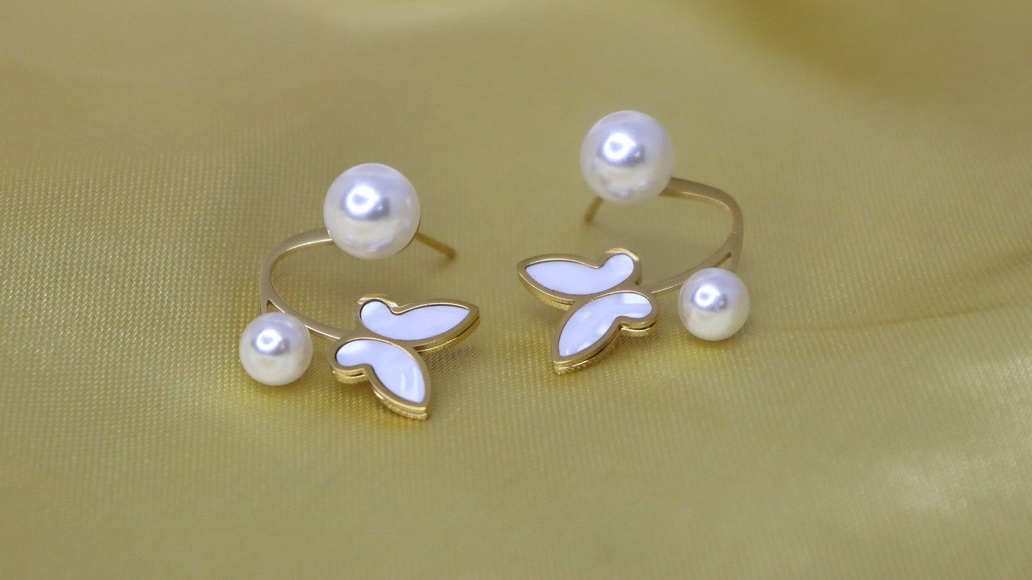 Pair of pearl earrings on a light yellow fabric background