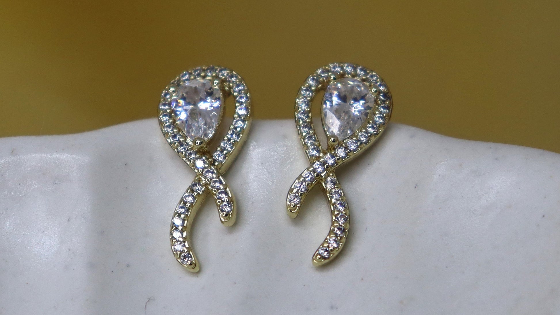 Pair of silver earrings with heart-shaped gemstones on a white shell.