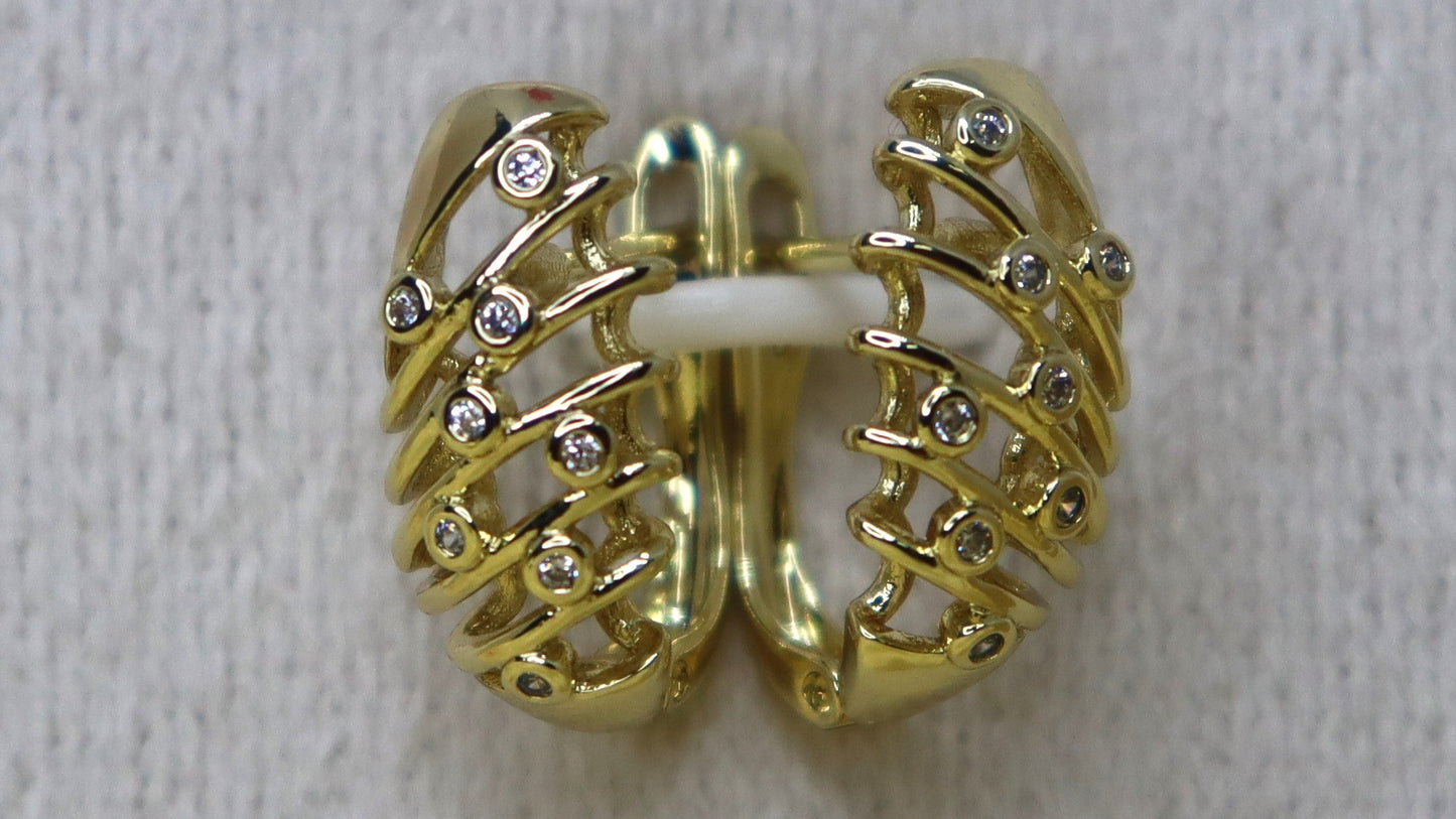 Gold earring on a textured white surface