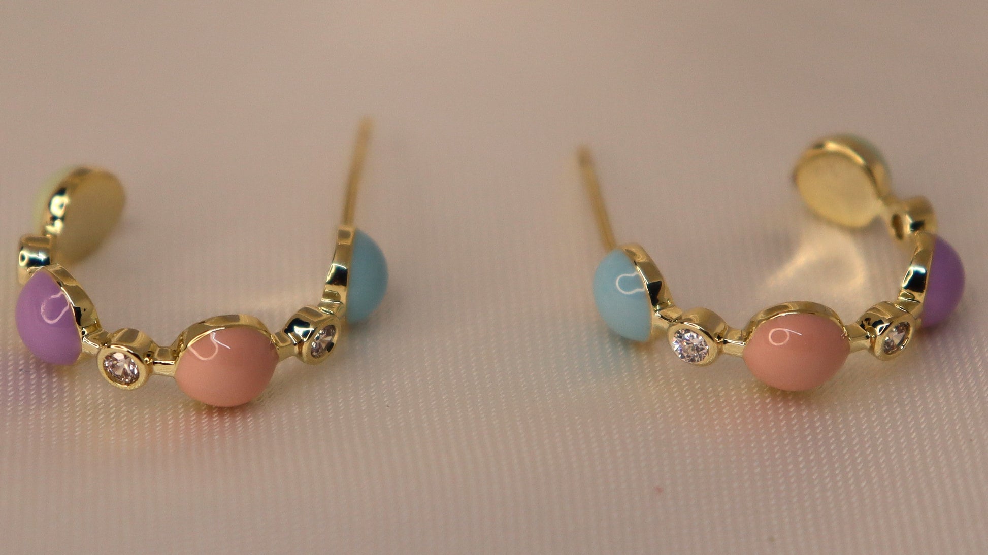 Pair of gold hoop earrings with colorful beads on a light background