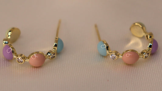 Pair of gold hoop earrings with colorful beads on a light background