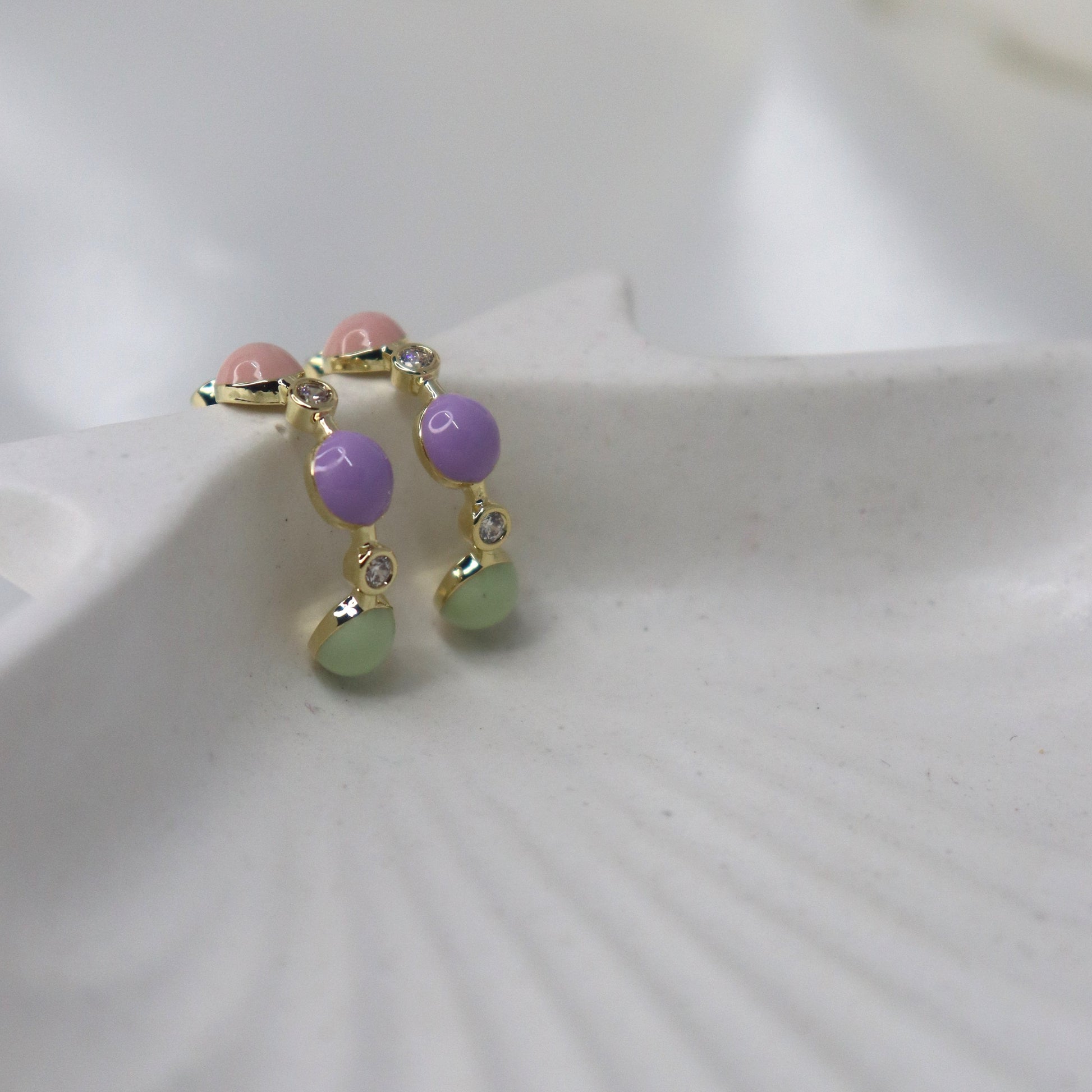Small earring with colorful beads on a white shell background