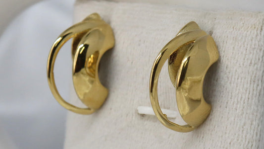 Gold hoop earrings on a white jewelry display