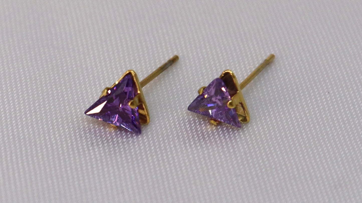 Pair of gold-trimmed purple gemstone stud earrings on a light gray background