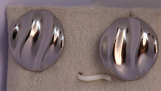 Two metallic hooks on a textured beige surface with a light purple wall background.
